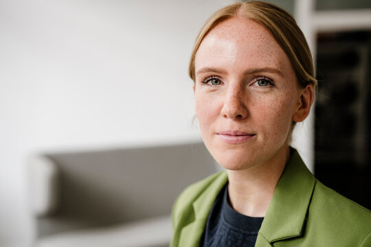 Portrait of a woman in green jacket in loft with copy space
