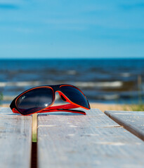 Sunglasses on wooden resting table on sandy beach of Jurmala - famous Baltic tourist  resort in Latvia, Europe. Sand beaches cover more than 26 km of coastline