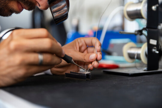 Lab technician soldering microchip in electronics workshop