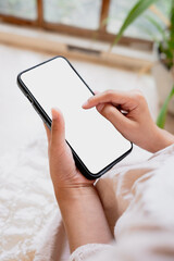 Smartphone in a young woman's hands with blank white screen with clipping path for app mockup and mobile design presentation
