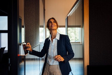 Businesswoman using touchscreen light sensor in modern office meeting room