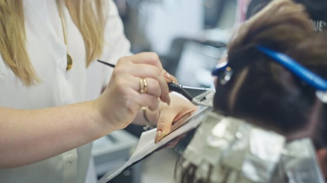 Stylist applying hair bleach close up in salon while coloring woman hair showing professional hairdresser service hairstyle transformation and beauty care