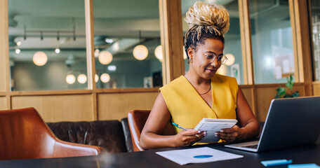 Woman in yellow working at a laptop in an open office