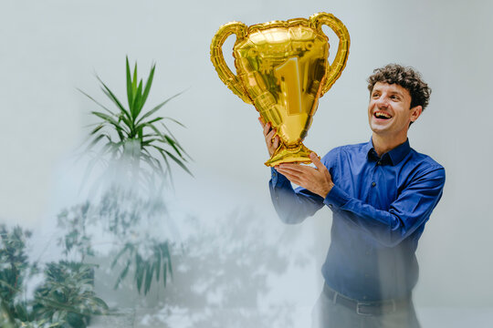 Businessman celebrating achievement with trophy balloon in office