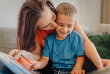 Mother kissing son while reading book at home