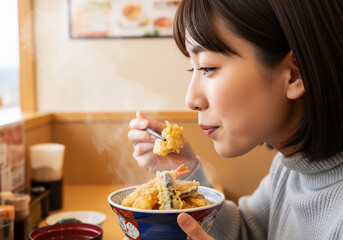 湯気立つ絶品の天丼を幸せそうに味わう日本人女性