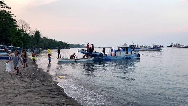 Men of Asian appearance, fishermen load ice and are going to go to sea at sunset to fish on traditional boats