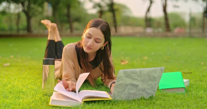 Indian young adult gen z busy lady female use laptop look screen check online new e work skill in fresh air park. Happy pupil girl lying on grass do study read book turn pages spend break time place