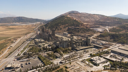 Aerial drone footage of a massive cement factory next to a quarry on a mountainside. Industry, environment, production, and raw materials.