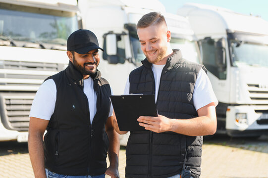 Truck drivers discussing logistics on clipboard smiling