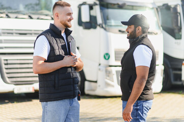 Two truck drivers discussing logistics next to semi trailers