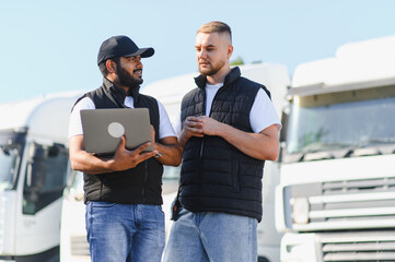 Truck drivers discussing logistics using laptop at fleet depot