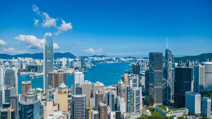 Latest October 2025 aerial view of Hong Kong business skyscrapers, Victoria Harbour, Kowloon and Hong Kong Island in beautiful clean sky and fluffy cloud © Shing