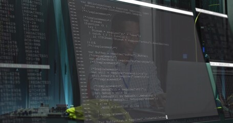 Typing African American developer coding JavaScript in server room, with monitor and server racks