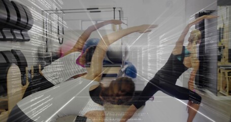 Guiding pilates instructor wearing leggings doing side stretch on reformers in studio with barrels