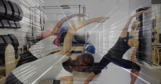 Fototapeta Guiding pilates instructor wearing leggings doing side stretch on reformers in studio with barrels