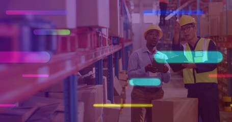 Inspecting staff in hardhats checking tablet and pointing up at racks of boxes in warehouse aisle