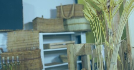 Displaying wheat stalks in clear vase at shop corner, baskets, bottles on shelving unit, copy space
