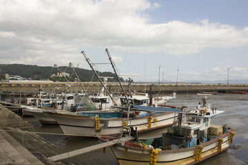 It is a tidal flat near the sea with anchored fishing boats.
