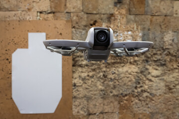 An FPV drone hovers before a silhouette, a concept of a modern moving target for shooting practice and anti-drone training.