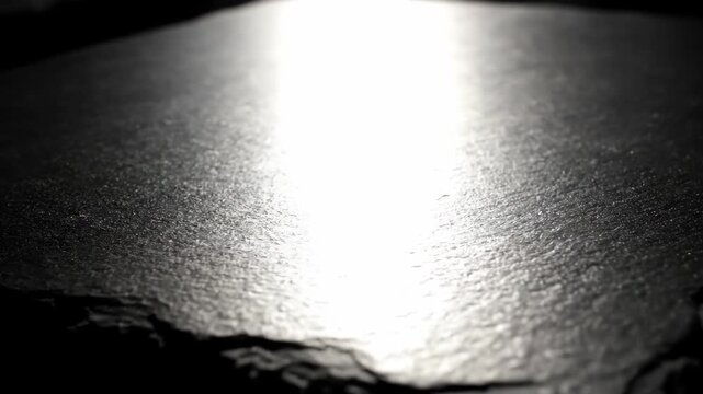 Dark slate surface with textured pattern and bright light reflection