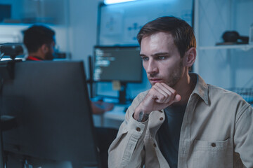 Male software developer working in modern office, analyzing code on computer screen.Male IT support specialist focused on customer service,Concept of programming, cybersecurity, and tech industry.