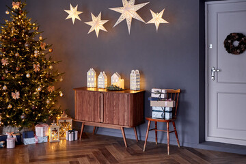 Cozy Christmas interior with glowing tree and golden ornaments. Elegant holiday decor with stars, gifts, and warm wooden tones. Peaceful winter atmosphere filled with light, beauty, and celebration.