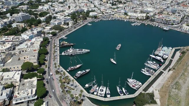 Aerial view of the Kos harbour showcasing boats resting on the water, framed by the city's architecture, Kos, Greece.