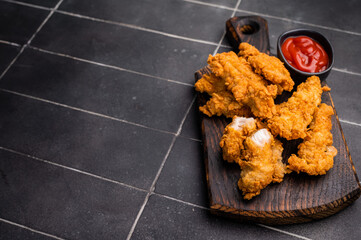Fried chicken tenders or strips with hot sauce. black background. top view
