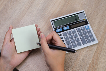 Focused Professional Carefully Records Important Financial Data Into Blank Note With Pen