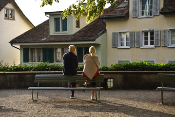 A Couple Sitting in Front of Traditional Houses at a Lindenhof Lookout Point in Zurich, Switzerland