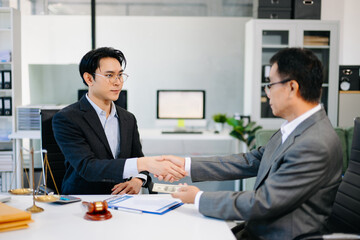 Lawyer and client shaking hands after contract signing with money and gavel on desk. Ideal for business, finance, partnership, or legal themes.
