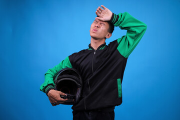 Young Asian Online Motorcycle Taxi Driver in Uniform Looking Exhausted and Wiping His Forehead With...