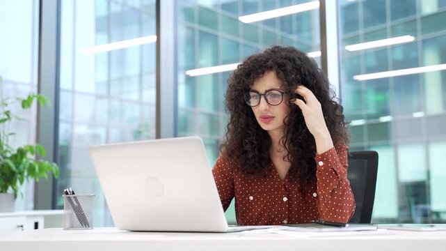Frustrated businesswoman having difficulty making transaction using laptop sitting at desk at workplace in a modern business office. Confused female worker having problems working online on computer