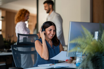 Smiling businesswoman with headset working at modern office desk