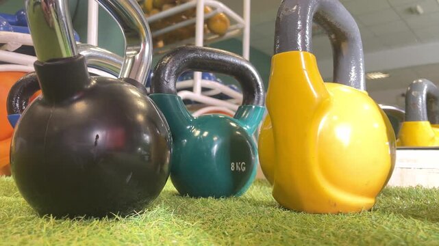 A green and black kettle sits on a green grassy area. The kettle is labeled 8 kg