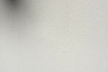 Construction and renovation work, plastering load-bearing street walls in sunlight. The white walls are coated with rough street primer with long micro-cracks throughout the surface and background.