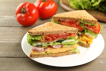 Tasty sandwiches with ham, cheese and vegetables on wooden table, closeup