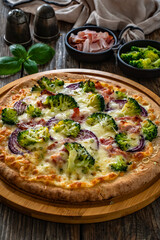 Pizza with bacon, broccoli and red onion on wooden table