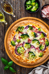 Pizza with bacon, broccoli and red onion on wooden table. Top view