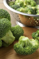 Fresh raw broccoli and colander on table, closeup