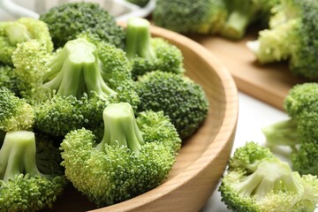 Fresh green broccoli in bowl on white table, closeup