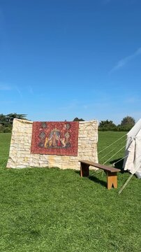 Panning Across a Wooden Rack Displaying Medieval Weapons, Shield, and Reenactment Tent