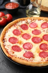 Delicious pepperoni pizza and ingredients on black table, closeup