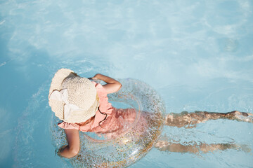 Cute funny toddler girl in a sunglasses relaxing on inflatable toy ring floating in pool have fun during summer vacation. Child having fun in swimming pool. 