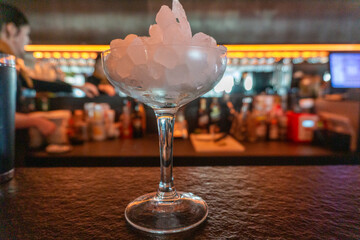 Cocktail glass filled with ice on bar counter