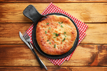 Delicious Megrelian khachapuri with parsley served on wooden table, top view