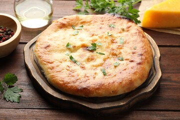 Delicious Megrelian khachapuri with ingredients on wooden table, closeup