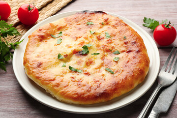 Delicious Megrelian khachapuri with parsley served on wooden table, closeup