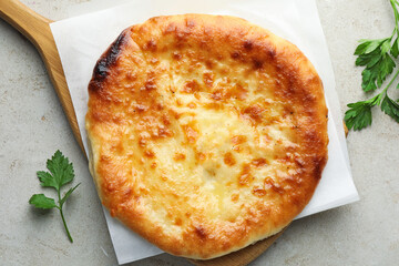 Delicious Megrelian khachapuri with parsley on grey table, top view